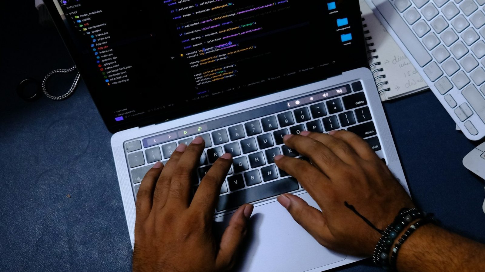 A developer's hands typing on a laptop with code open in a dark editor.